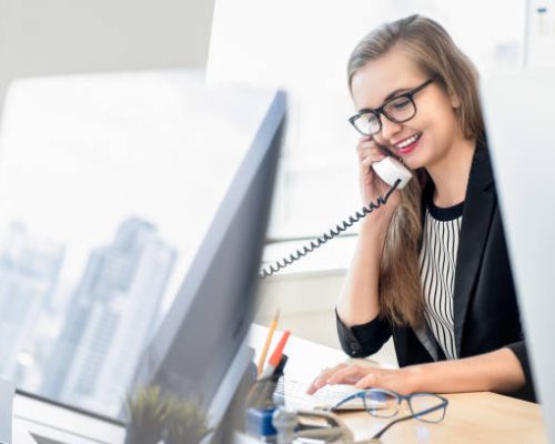 Happy businesswoman as a customer care representative talking on the phone at work with her client in the office